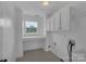 Well-lit laundry room featuring white cabinets, counter space, tile floors, and a utility sink hookups at 3068 River Rd, Shelby, NC 28152