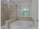 Elegant bathroom featuring a soaking tub, separate glass shower, and tiled walls at 308 Planters Way, Mount Holly, NC 28120