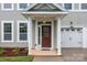 Charming covered entryway featuring a red front door, white columns, and well-maintained landscaping at 308 Planters Way, Mount Holly, NC 28120