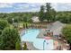 Aerial view of the community pool, surrounded by trees, playground, and patio furniture at 308 Planters Way, Mount Holly, NC 28120
