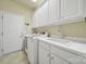Bright laundry room features white cabinets, utility sink, modern washer, and neutral tile floors at 35115 Carnation Ln, Fort Mill, SC 29707