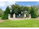 Stone entrance to Peach Orchard Estates with lush landscaping, manicured lawns, and wrought iron fencing at 3807 Blazeprince Dr, Charlotte, NC 28215