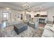 Comfortable living room showcases a modern chandelier, an ottoman, and seamlessly connects to the open-concept kitchen at 3807 Blazeprince Dr, Charlotte, NC 28215