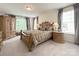 Serene primary bedroom with soft carpet, a carved wooden bed frame, and natural light from large windows at 3807 Blazeprince Dr, Charlotte, NC 28215
