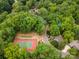 An aerial shot showcases community tennis and bocce ball courts enveloped by lush trees and winding paths at 449 Windward Dr, Davidson, NC 28036