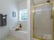 Bright bathroom featuring a tub with gold fixtures and a stand-up shower with gold trim at 4637 Willow Glen Rd, Harrisburg, NC 28075