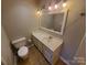 Bathroom featuring a toilet, sink with vanity, and a large mirror with vanity lighting at 5003 Sharon Rd # Q, Charlotte, NC 28210
