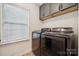 Functional laundry room with modern washer and dryer, storage cabinets, and a window at 5113 Saddleback Dr, Mount Holly, NC 28120