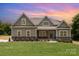 New home showcases stone accents, a covered porch, and a lush green lawn at sunset at 5408 Unionville Brief Rd, Unionville, NC 28110