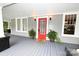 Inviting front porch featuring a bright red door, gray flooring, and decorative potted plants at 616 N Deal Ave, Newton, NC 28658