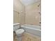 Clean bathroom featuring a white bathtub, standard toilet, and neutral-toned tile flooring at 6401 Windsor Gate Ln, Charlotte, NC 28215