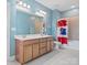 Large bathroom with double sink vanity, toilet and tiled tub with a red, white, and blue shower curtain at 6535 Bridgemoor Dr, Indian Trail, NC 28079
