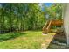Expansive backyard with a wooden deck and stairs leading down to the lush, green lawn surrounded by mature trees at 7018 Rollingridge Dr, Charlotte, NC 28211