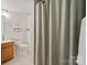 Cozy bathroom featuring a tile floor, wood vanity, toilet and shower with gray curtain at 7018 Rollingridge Dr, Charlotte, NC 28211