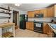 Efficient kitchen showcasing wood cabinets, black appliances, and easy-to-clean tile flooring at 7018 Rollingridge Dr, Charlotte, NC 28211