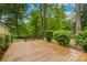 Landscaped backyard features a wooden deck surrounded by mature trees, providing a tranquil outdoor retreat at 7022 Lakeside Dr, Charlotte, NC 28215