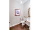 Stylish powder room with pedestal sink, decorative mirror, and hardwood floors at 8070 Clems Branch Rd, Indian Land, SC 29707