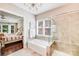 Bathroom featuring a bathtub, stand-up shower, and a chandelier above, with neutral colors and tiled walls at 8070 Clems Branch Rd, Indian Land, SC 29707