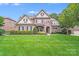 Beautiful brick home featuring manicured lawn, stone accents, mature trees, and a charming front porch at 8070 Clems Branch Rd, Indian Land, SC 29707