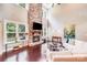 Well-lit living room boasts a stone fireplace, hardwood floors, and large windows at 8070 Clems Branch Rd, Indian Land, SC 29707