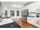 Kitchen with white cabinets, black countertops, stainless steel refrigerator and hardwood flooring and large bright windows at 8256 Chatham Oaks Dr, Concord, NC 28027