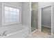 Bathroom featuring a windowed soaking tub, glass enclosed shower, and an open closet space at 105 Stumpy Creek Rd, Mooresville, NC 28117