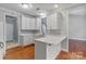 Well-lit kitchen with white cabinetry, quartz countertops, stainless sink, and wood flooring at 105 Stumpy Creek Rd, Mooresville, NC 28117