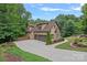 Charming two-story home featuring a three-car garage, stone accents, well-manicured landscaping, and a curved driveway at 117 Walking Horse Trl, Davidson, NC 28036