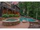 Beautiful backyard with a stone-trimmed pool and spa, as well as a raised deck and patio area, all surrounded by lush landscaping at 117 Walking Horse Trl, Davidson, NC 28036