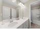 Bright bathroom featuring double sinks, large mirror, and shower-tub combo at 15515 Laverack Ln, Davidson, NC 28036