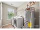 Laundry room equipped with a washing machine, dryer, utility sink, water heater, and shelving at 15515 Laverack Ln, Davidson, NC 28036