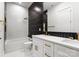 Bright bathroom with double vanity, black accent wall, white tile, and gold fixtures at 1626 Burtonwood Cir, Charlotte, NC 28212