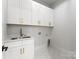 Bright Laundry room featuring white shaker cabinets, modern gold hardware, and tile floors at 1626 Burtonwood Cir, Charlotte, NC 28212