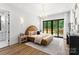 Cozy main bedroom with wood floors, modern lighting fixtures, balcony access with outdoor views and ensuite bathroom at 1626 Burtonwood Cir, Charlotte, NC 28212