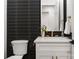 Close up of powder room featuring decorative black accent wall, white vanity, and gold fixtures at 1626 Burtonwood Cir, Charlotte, NC 28212
