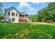 Expansive backyard featuring a white brick home, screened porch, lush lawn, and mature trees at 167 Logan Crossing Dr, Davidson, NC 28036