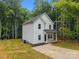 View of new construction featuring white siding, black roof, covered porch and driveway at 1723 Rhyneland Cir, Gastonia, NC 28054