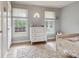 Bedroom with a white dresser, two windows, hardwood floors, and a cozy rug, providing comfort and style at 1821 Bonnie Ln, Charlotte, NC 28213