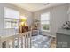 Cozy Bedroom featuring a crib, a gray rocking chair, and natural light from multiple windows at 1821 Bonnie Ln, Charlotte, NC 28213