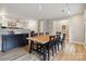 Light-filled dining room featuring a large wooden table with black chairs, hardwood floors, and a view of the living area at 1821 Bonnie Ln, Charlotte, NC 28213