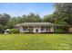 Inviting home with a covered front porch, surrounded by lush greenery at 1821 Bonnie Ln, Charlotte, NC 28213