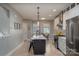 Well-lit kitchen with an island, bar stools, white cabinets and stainless steel appliances on hardwood floors at 2011 Hamorton Pl, Charlotte, NC 28205