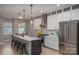 Modern kitchen with an island featuring bar stool seating, white cabinets, and stainless steel appliances on hardwood floors at 2011 Hamorton Pl, Charlotte, NC 28205