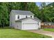 View of the side and front of the home and attached garage, surrounded by mature trees at 2025 Slater Rd, Charlotte, NC 28216