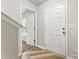 Hallway with wood floors, a white door, and an open doorway to a sunlit room at 2025 Slater Rd, Charlotte, NC 28216