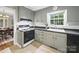 Well-lit kitchen with gray cabinets, black countertops, window view and gas range stove, connected to dining area at 2026 Knell Dr, Charlotte, NC 28212