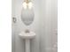 Powder room featuring a pedestal sink, oval mirror, and modern lighting fixture at 230 Dawn Mist Ln, Fort Mill, SC 29708