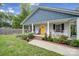 Inviting front porch with rocking chairs and a cheerful yellow door, surrounded by lush landscaping and a brick-lined flowerbed at 2302 Douglas Rd, Lancaster, SC 29720