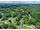 Expansive aerial view showcasing a neighborhood surrounded by lush, mature trees and greenery at 240 Hillcrest Dr, Harrisburg, NC 28075