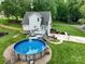 Aerial view of backyard featuring a round pool with deck, patio seating, and well-manicured yard at 240 Hillcrest Dr, Harrisburg, NC 28075
